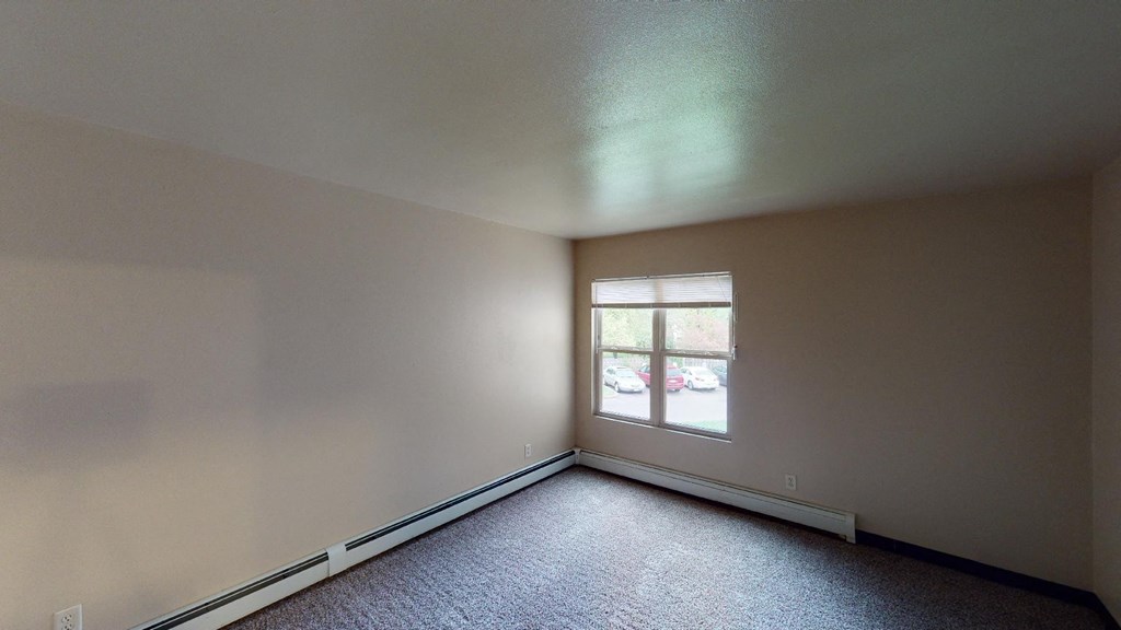 A room with a window and a car parked outside.