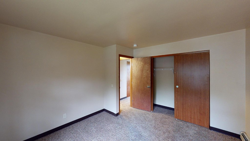 A room with a carpeted floor and two wooden doors.