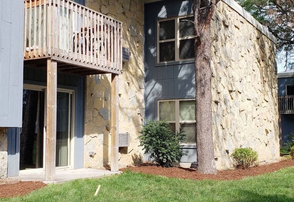 A building with a balcony and a tree in front of it.