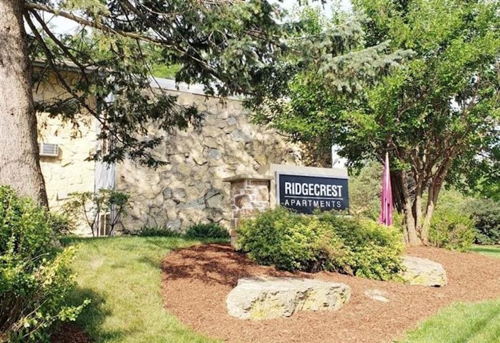 A sign for Ridgecrest Apartments is surrounded by greenery.
