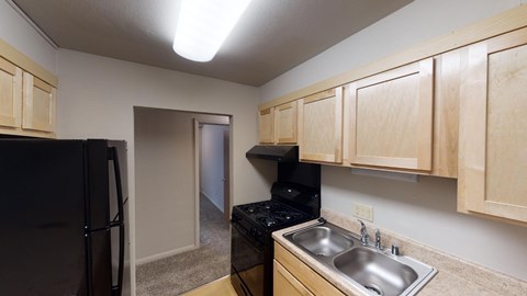 A kitchen with wooden cabinets and a black fridge.