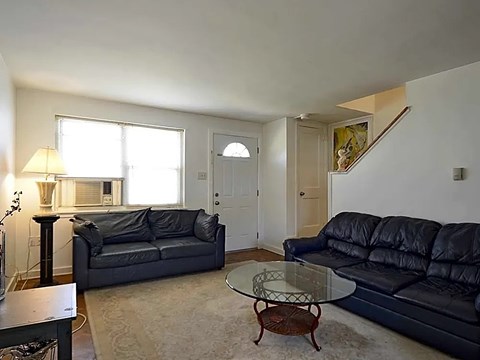 A living room with a black couch and a glass table.