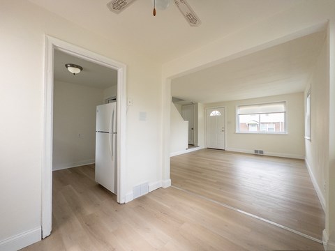 A kitchen with a refrigerator and a doorway leading to another room.