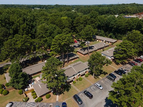 A parking lot with cars and a building surrounded by trees.