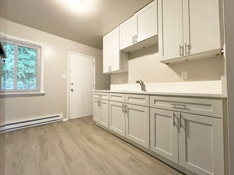 A kitchen with white cabinets and a window.