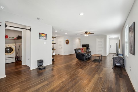 A living room with a black leather couch and a ceiling fan.