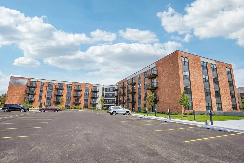 A parking lot in front of a brick apartment building.
