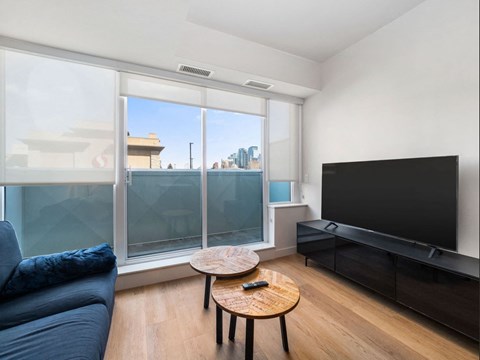 A living room with a blue couch, a wooden coffee table, and a flat screen TV.