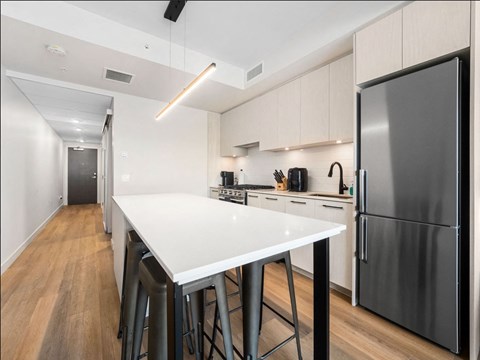 A modern kitchen with a white countertop and stainless steel appliances.