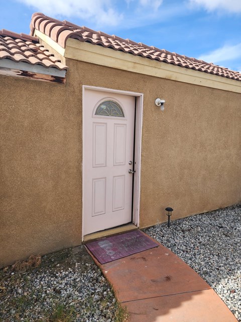 A small brown house with a white door and a brown mat in front.