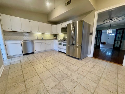 A kitchen with white cabinets and a tile floor.