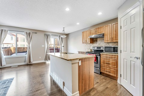 A kitchen with wooden cabinets and a white island.