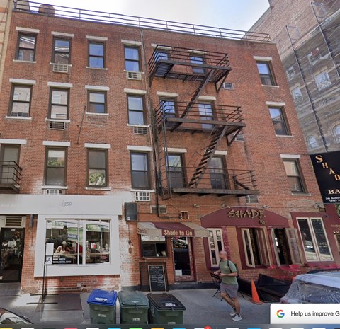 A man is walking past a red brick building with a Shade storefront.