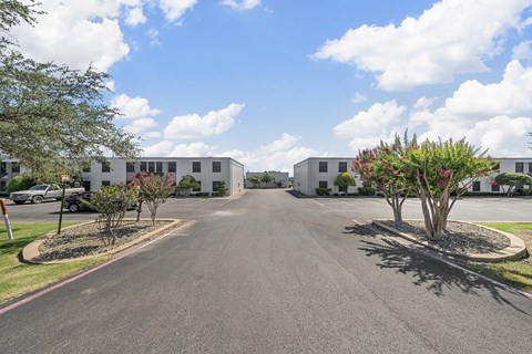 A road leads to a building with a parking lot in front.