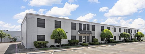 A white building with a black roof and a parking lot in front.