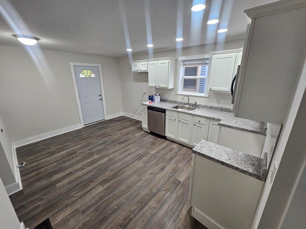 A kitchen with white cabinets and a wooden floor.