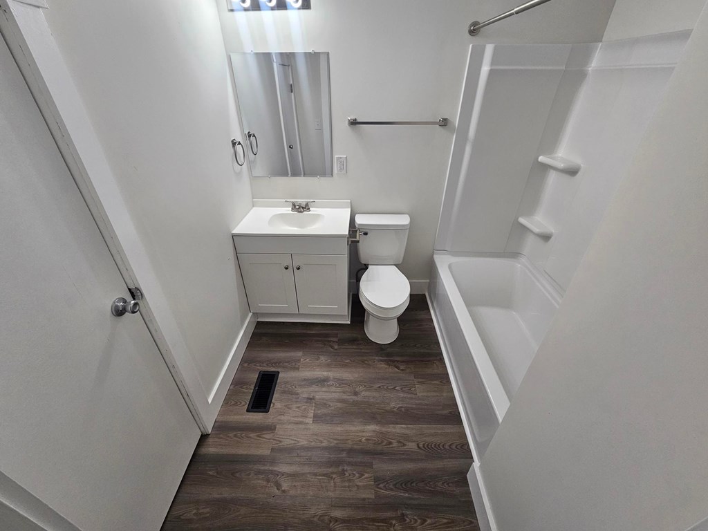 A bathroom with a toilet, sink, and mirror.