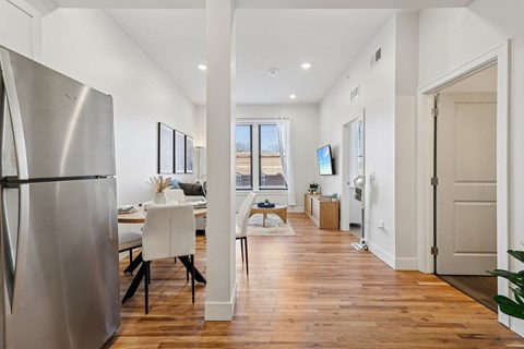 A modern kitchen with a stainless steel refrigerator and wooden flooring.