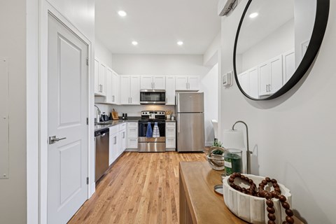 A modern kitchen with wooden floors and stainless steel appliances.