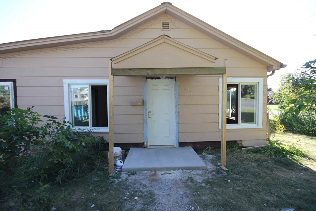 A small beige house with a white door and windows.