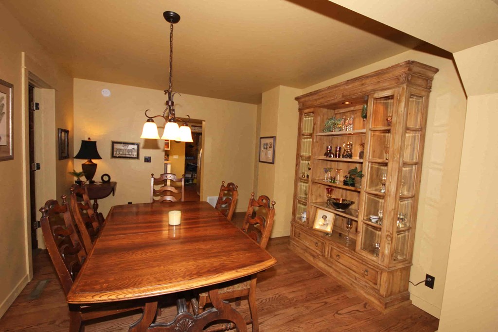 A wooden dining table with chairs and a chandelier hangs in a room.