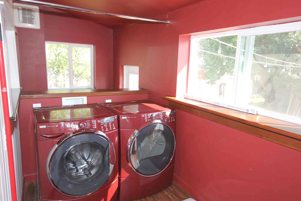 Two red front loading washing machines in a laundry room.