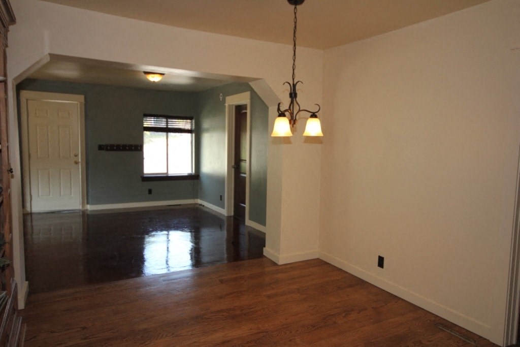 A room with wooden floors and a chandelier hanging from the ceiling.