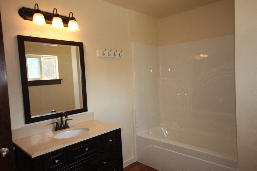 A bathroom with a sink, mirror, and bathtub.