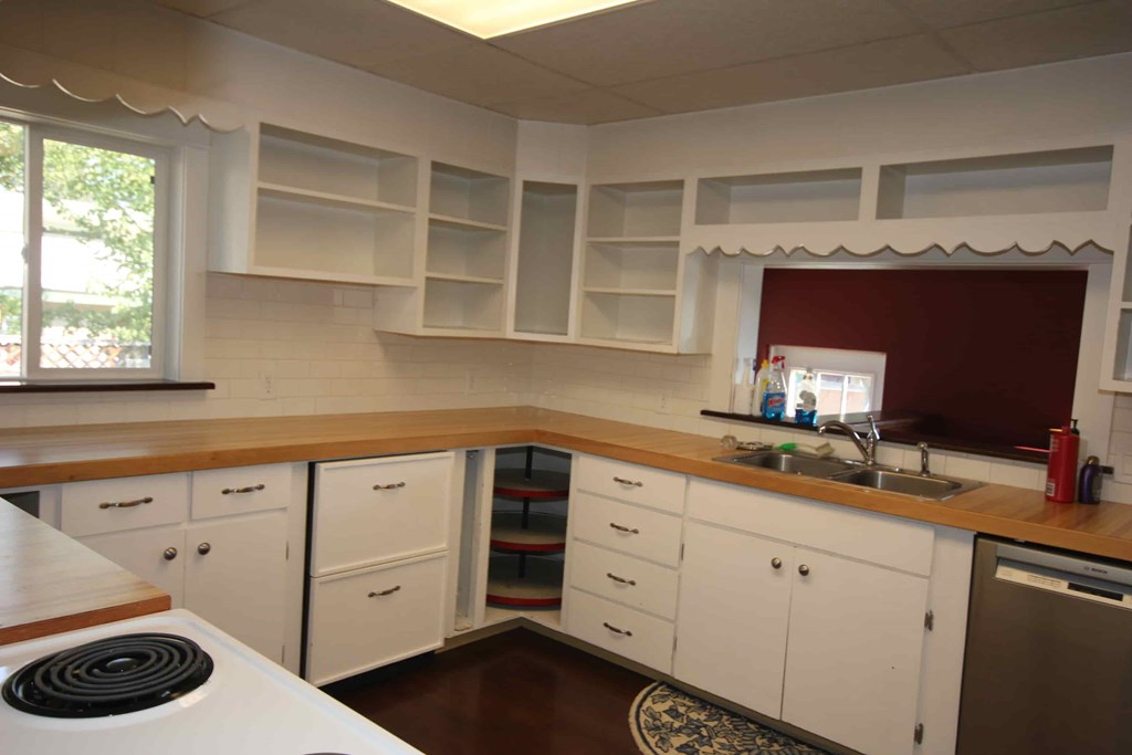 A kitchen with white cabinets and a wooden counter.