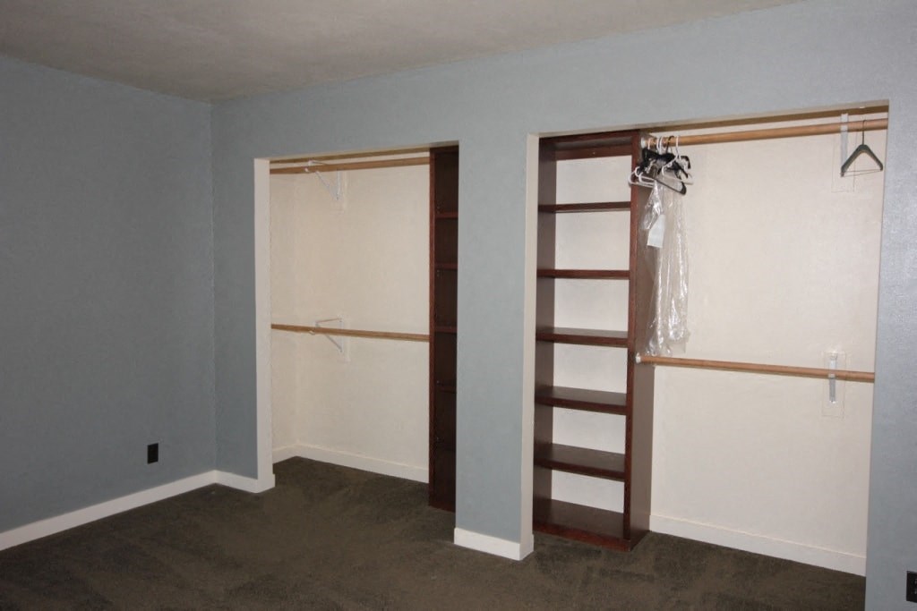 A room with a ladder and clothes hanging on a rack.
