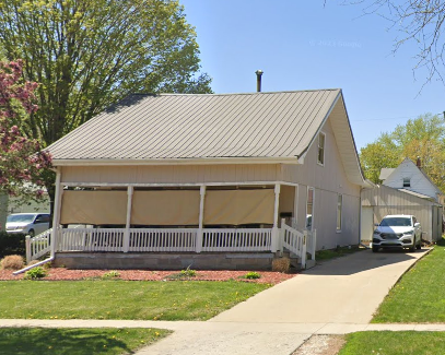 A house with a covered porch and a car parked in front.