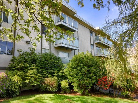 Apartment building with green bushes in front.