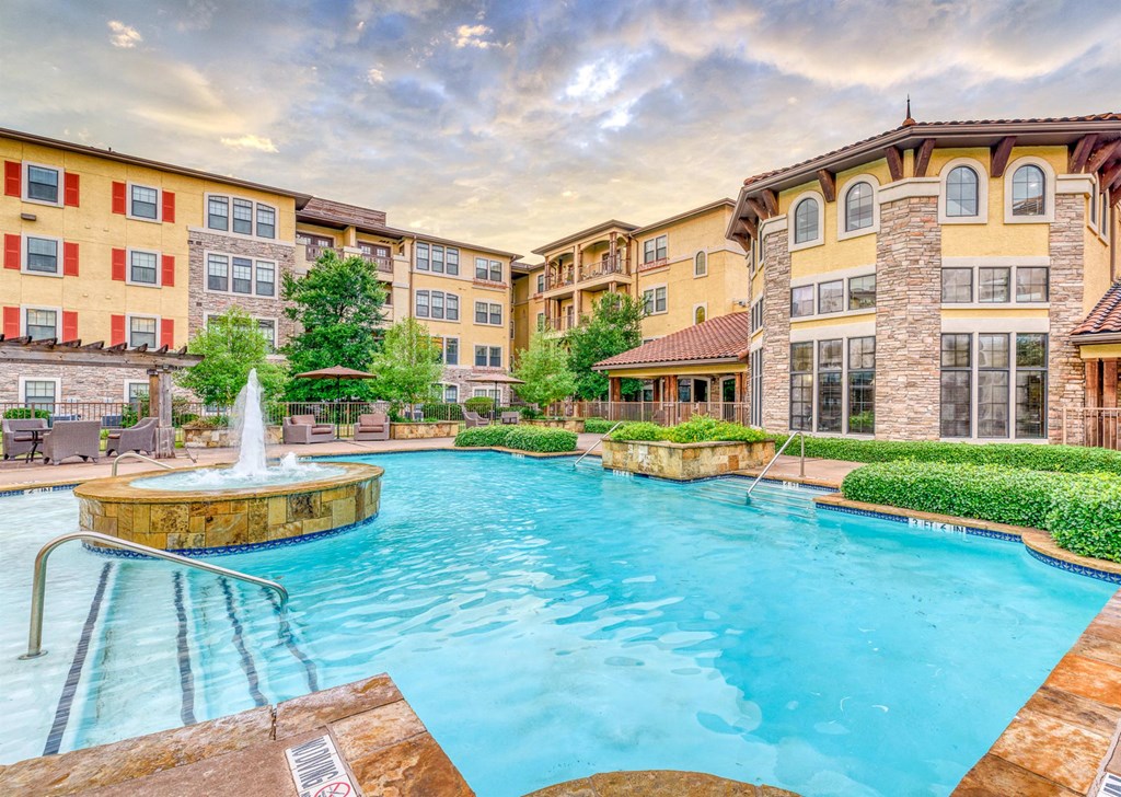 A large outdoor pool with a fountain in the middle of a residential area.