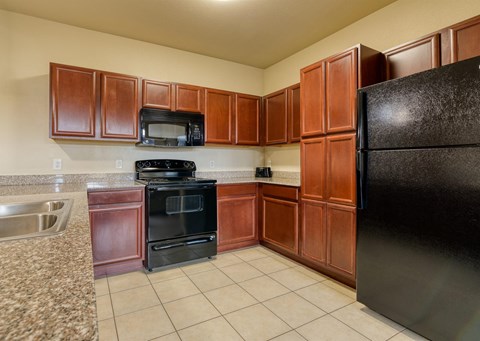 A kitchen with brown cabinets and black appliances.