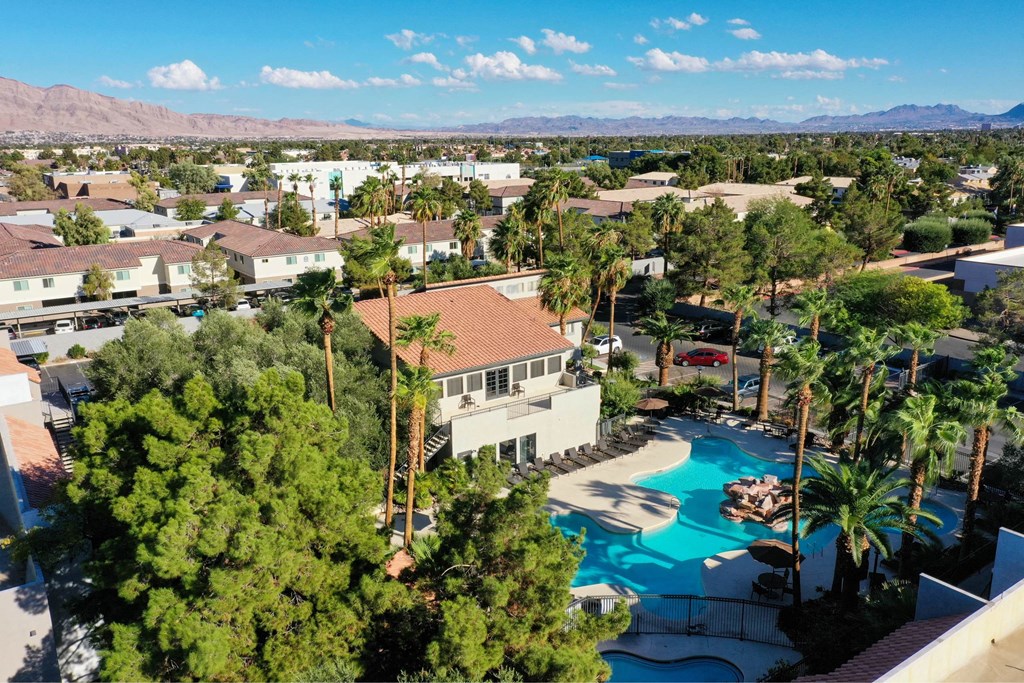 A pool surrounded by palm trees and a mountain range in the background.