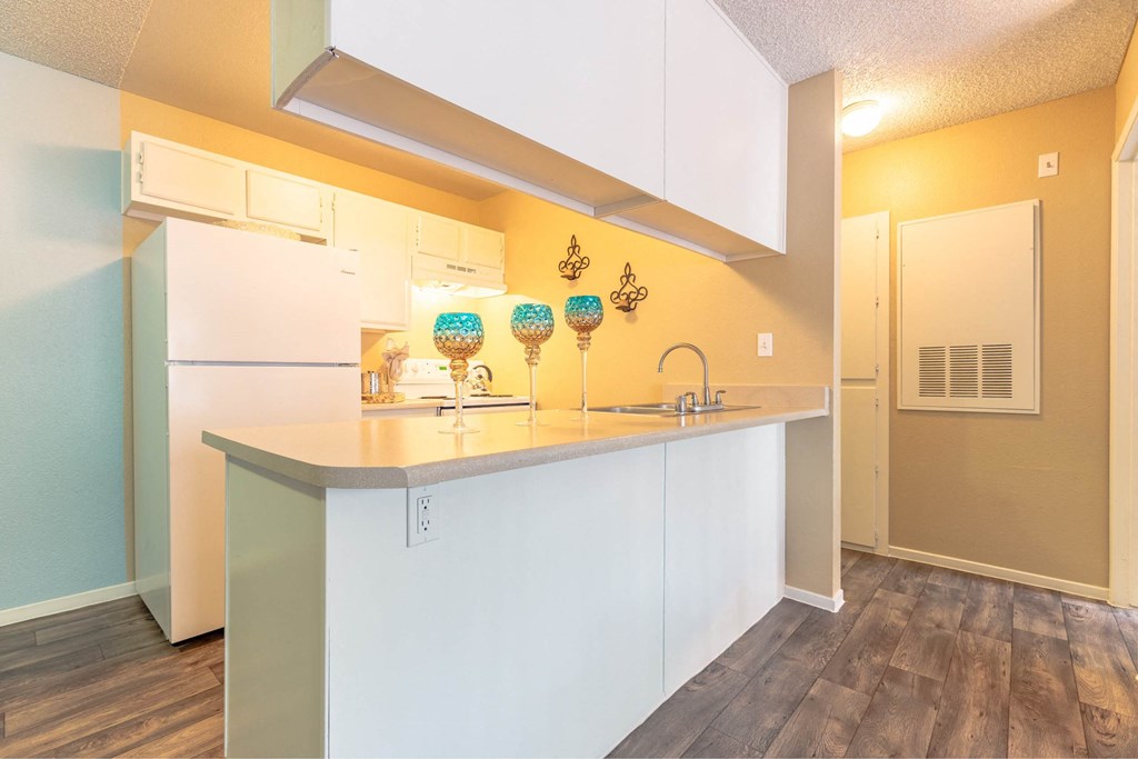 A kitchen with white cabinets and a white fridge.