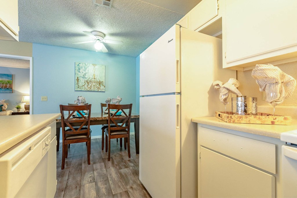 A kitchen with a white refrigerator, two chairs, and a table.