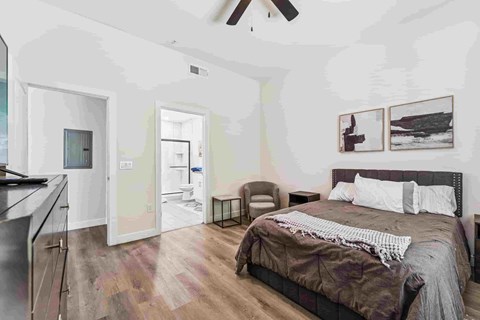 A bedroom with a bed, chair, and pictures on the wall.