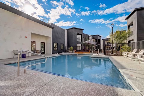 A swimming pool in front of a building with a sunny sky.