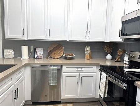 A kitchen with white cabinets and black appliances.