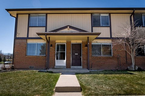 A small house with a brown door and a small porch.