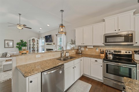A kitchen with white cabinets and a granite countertop.