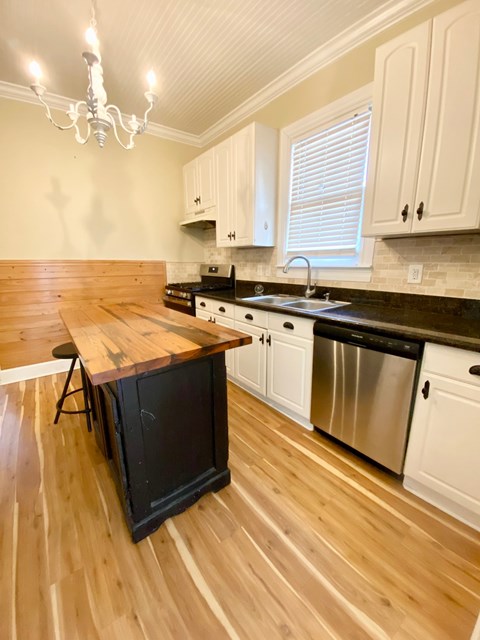 A kitchen with wooden floors and white cabinets.