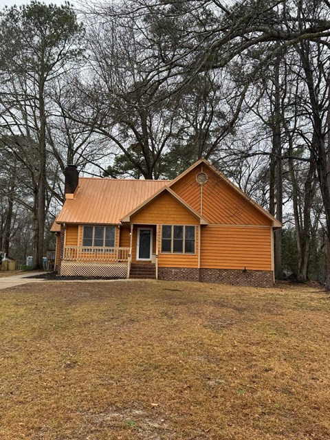 A small wooden house with a brown roof and a porch.