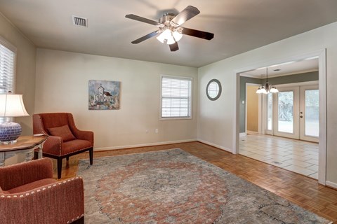 A living room with a ceiling fan and a painting on the wall.