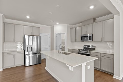 A modern kitchen with a white island and stainless steel appliances.