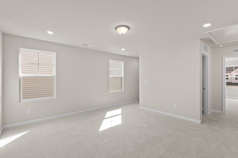 A spacious room with a carpeted floor and a window with blinds.