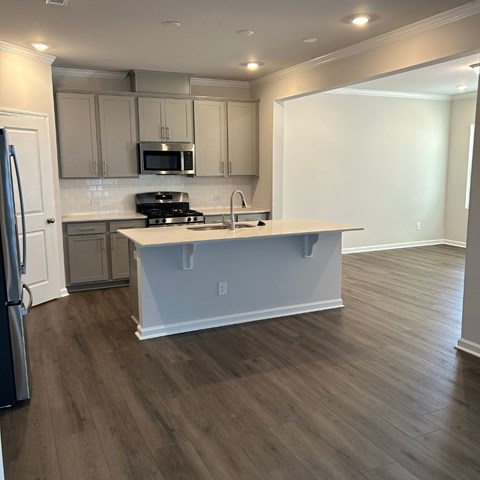 A kitchen with a refrigerator, microwave, and oven.