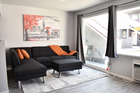 A living room with a grey couch and a red and orange throw.