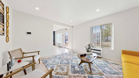 A living room with a rug and a yellow couch.